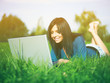 Foto: Young woman using laptop in park Young woman using laptop in park
