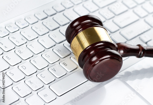 Photo: Close up of wooden gavel at the computer keyboard Close up of wooden gavel at the computer keyboard
