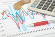 Photo: Calculator, coins and pen laying on chart Calculator, coins and pen laying on chart