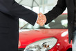 Handshake of two men in suits with a red car