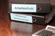 Arbeitsschutzordner mit Taschenrechner auf Chef Schreibtisch