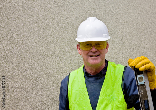 Photo: Construction worker leans on spirit level Construction worker leans on spirit level