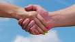A man and woman shaking hands on blue sky background