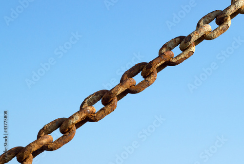 Photo: Old rusty metal chain links and a blue sky. Old rusty metal chain links and a blue sky.