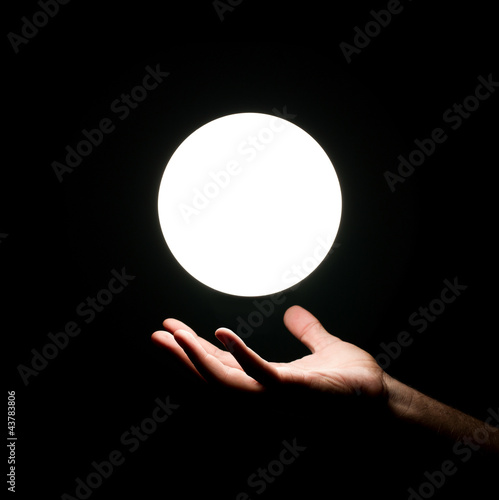 Photo: Bright light ball over human hand isolated on black background Bright light ball over human hand isolated on black background