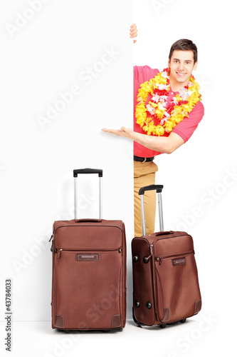 Photo: Young man with suitcases posing behind panel Young man with suitcases posing behind panel