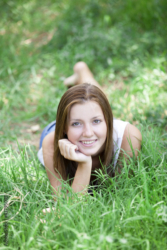 Foto: Beautiful teen girl in the park at green grass. Beautiful teen girl in the park at green grass.