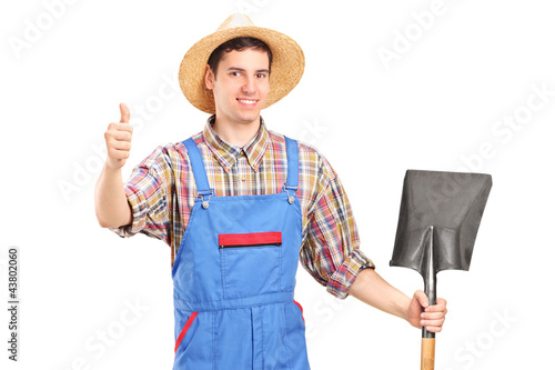Foto: A male agricultural worker holding a shovel and giving a thumb u A male agricultural worker holding a shovel and giving a thumb u