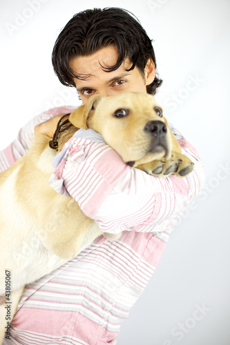 Photo: Young man kissing his puppy dog labrador Young man kissing his puppy dog labrador
