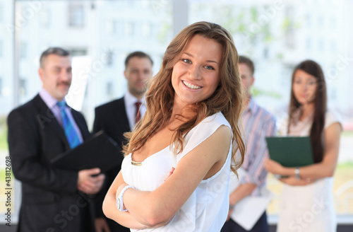 Photo: Successful business woman standing with her staff at office Successful business woman standing with her staff at office