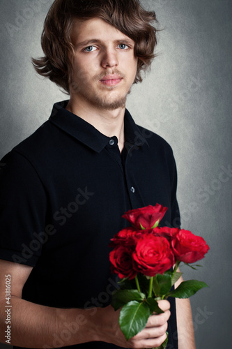 Photo: sad young man with bouquet of a red roses sad young man with bouquet of a red roses