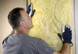 Worker installing fiberglass insulation on the wall