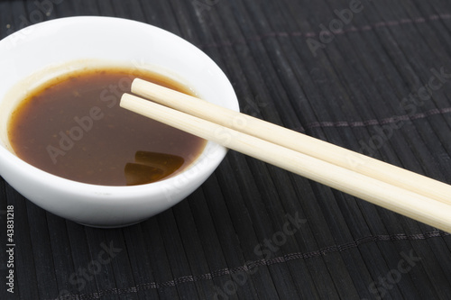 Photo: Hoisin & Chopsticks - Bowl of asian dipping sauce on a black mat Hoisin & Chopsticks - Bowl of asian dipping sauce on a black mat
