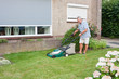 Dutch senior mowing lawn