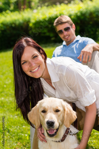 Foto: Couple sitting with golden retriever in park Couple sitting with golden retriever in park