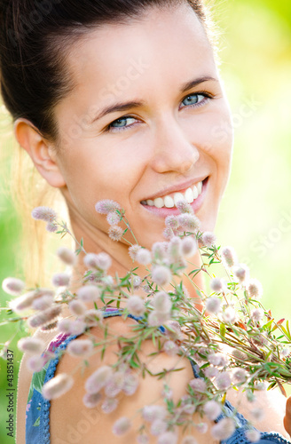 Foto: Beautiful woman with field plant in hands Beautiful woman with field plant in hands