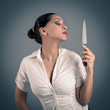 Photo: Sexy brunette woman holding a knife against dark background. Sexy brunette woman holding a knife against dark background.