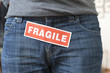 Midsection view of a person with a word 'Fragile' stuck on its jeans
