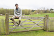 Man sitting on the gate of a cottage