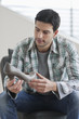 Photo: Man sitting on a couch and holding a high heel shoe Man sitting on a couch and holding a high heel shoe