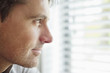 Close-up of a man looking through a window and thinking