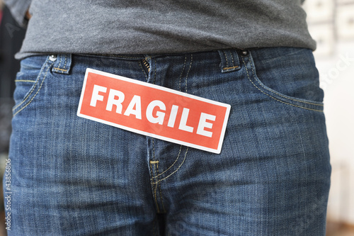 Photo: Midsection view of a person with a word 'Fragile' stuck on its jeans Midsection view of a person with a word 'Fragile' stuck on its jeans