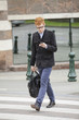 Businessman crossing a road while using a mobile phone