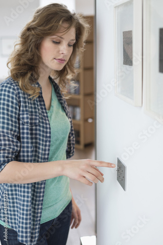 Photo: Woman pressing light switch on a wall Woman pressing light switch on a wall