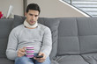 Man suffering from neckache and watching television