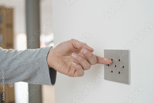 Photo: Close-up of a man's hand pressing light switch on a wall Close-up of a man's hand pressing light switch on a wall