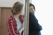 Two female friends standing back to back against a door
