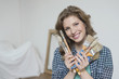 Portrait of a woman holding paintbrushes and smiling