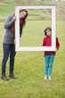 Woman and her son standing with a frame in a park