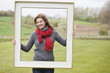 Portrait of a woman standing with a frame in a park