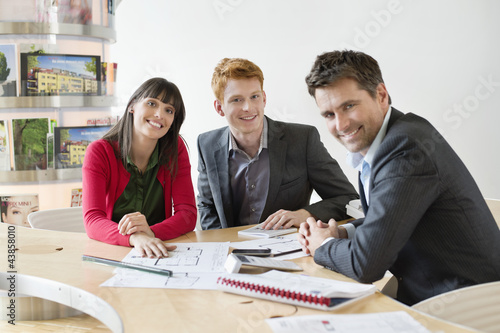 Photo: Real estate agent discussing property documents to his clients Real estate agent discussing property documents to his clients