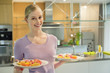 Happy woman holding two plates of cup cakes