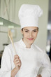 Happy female chef holding a wooden spoon