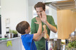 Man and son giving high five to each other in the kitchen