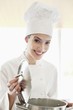 Happy female chef holding a saucepan