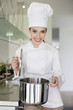 Happy female chef holding a saucepan