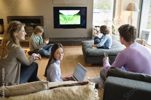 Photo: Family using electronic gadgets in a living room Family using electronic gadgets in a living room