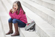 Schoolgirl sitting on the steps and eating pain au chocolat