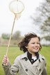 Boy running with a butterfly net in a park