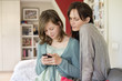 Girl text messaging on mobile phone with her mother at home
