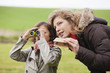 Boy looking through binoculars standing with his mother