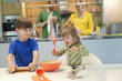 Children cooking in the kitchen with their parents in the background