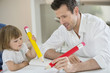 Man and daughter writing with big pencils