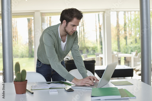 Photo: Man working on a laptop with a cactus plant on the table Man working on a laptop with a cactus plant on the table