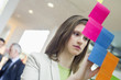 Businesswoman sticking memo notes on glass in an office