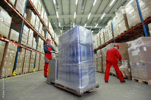 Photo: Warehousing - Two workers in uniforms working in storehouse Warehousing - Two workers in uniforms working in storehouse